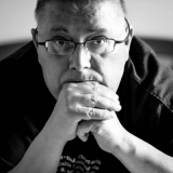 Black and white portrait photo of Gunnar Somby resting his head on his hands