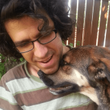 Portrait photo of Helio Povoas Neto and his dog cuddling under his chin