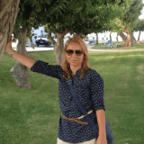 Portrait photo of Tanya Madzharova leaning on a tree in a park with green grass